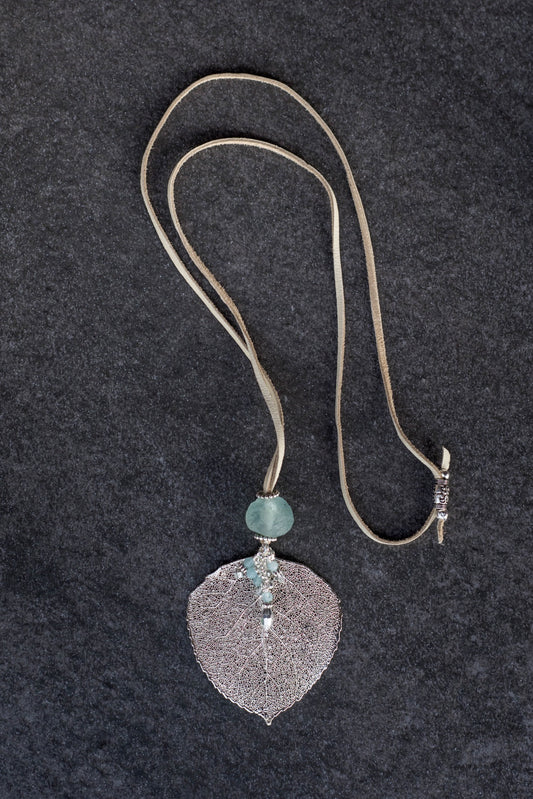 Single re-cycled African glass bead with a large silver Aspen leaf finished with a stunning crystal dangle .  Deerskin leather