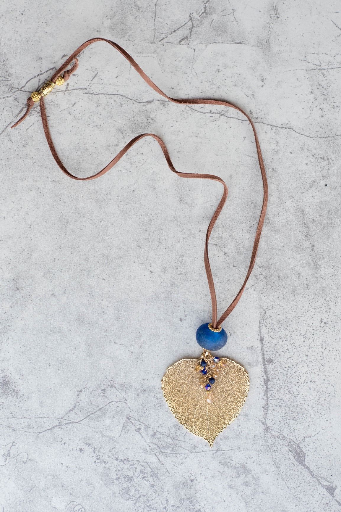 Single re-cycled African glass bead with a large Gold Aspen leaf finished with a stunning crystal dangle.  Deerskin leather