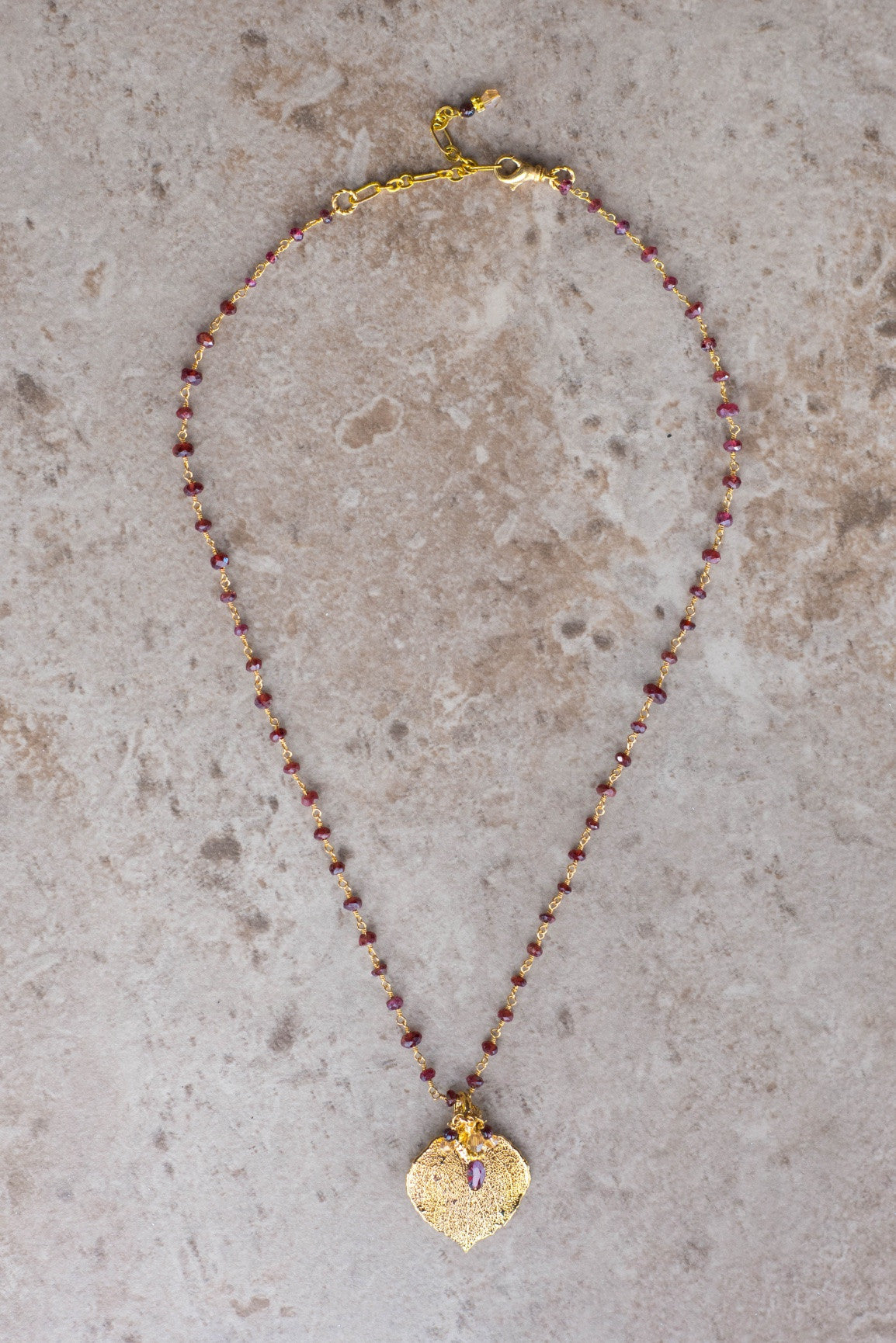 Gems in gold chain: Garnets accent the classic princess style necklace with a gold leaf