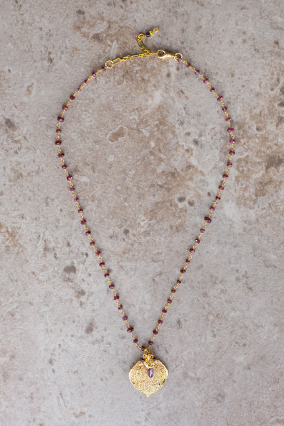 Gems in gold chain: Garnets accent the classic princess style necklace with a gold leaf