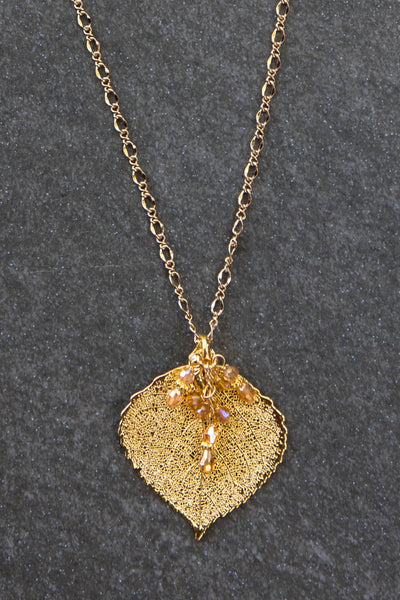 Classic Gold chain creates this striking long necklace with a Gold leaf and crystal dangles