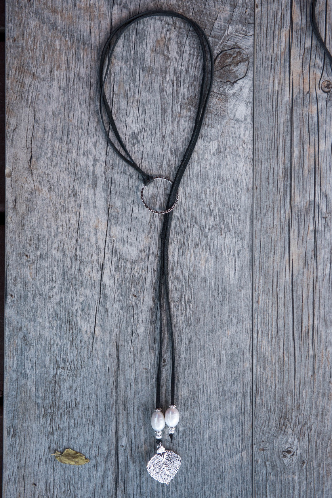 Two White pearls, silver leaf, black leather and pounded silver ring