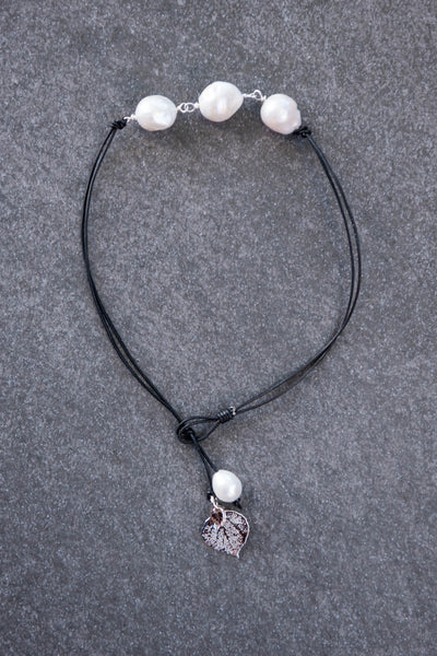Four pearls choker: Three white baroque pearls wire twisted with a Silver leaf and back white pearl, black leather cord.